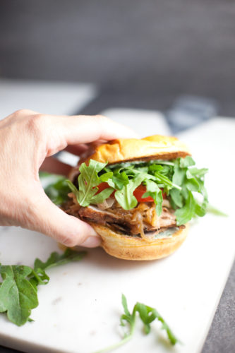 Pork Tenderloin Sandwich with lots of arugula being held