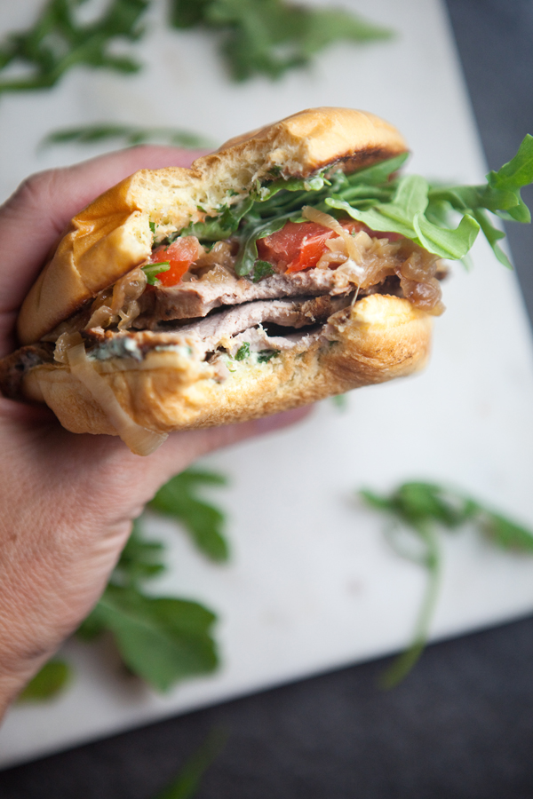 Pork Tenderloin Sandwich with lots of arugula on a cutting board
