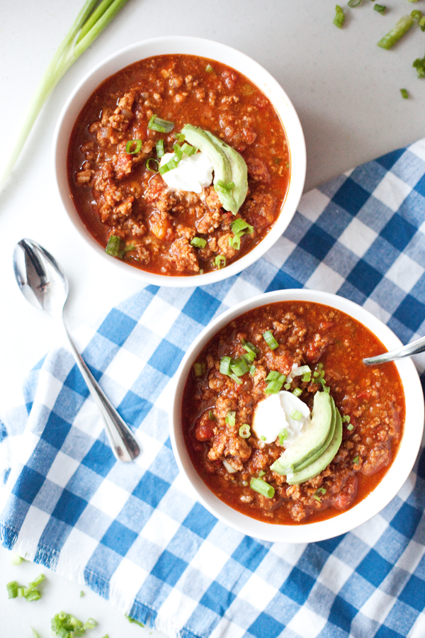 Two bowls of delicious topped chili on a checkered napkin