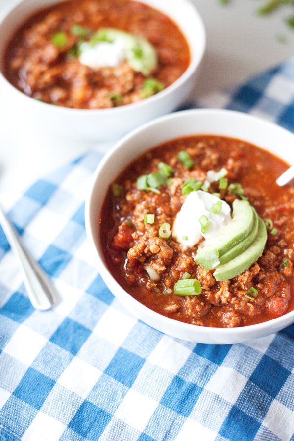 Two bowls of delicious topped chili on a checkered napkin
