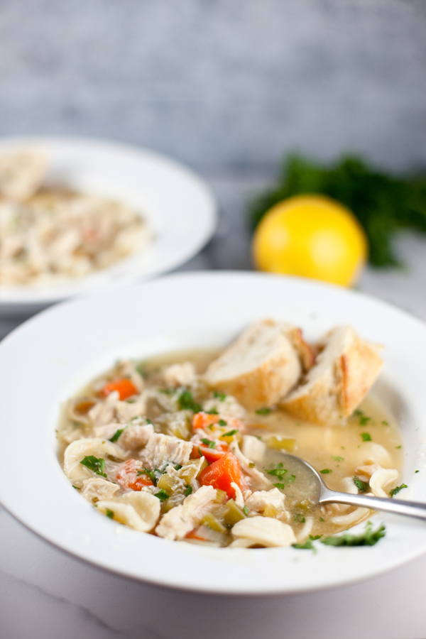 Two bowls of chicken soup with bread