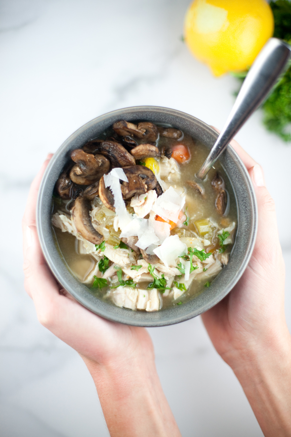 Bowl of lemony chicken soup with mushrooms on top