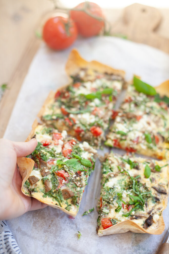 hand grabbing a bite of Garden Veggie Quiche for One | recipe by www.lillieeatsandtellscom.bigscoots-staging.com